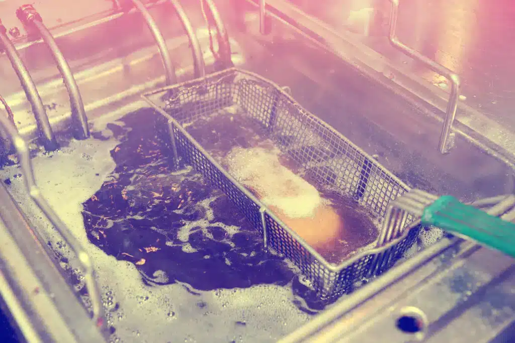 Commercial deep fryer basket with golden food - how cooking oil collection works