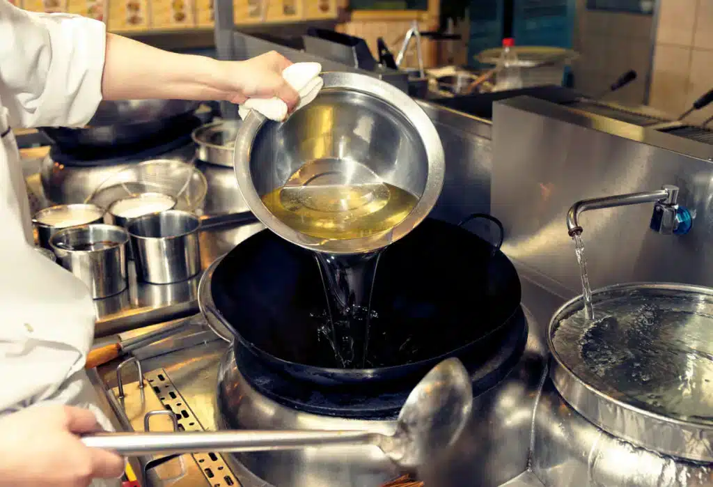 Chef pouring used cooking oil into collection container - free UCO collection service UK